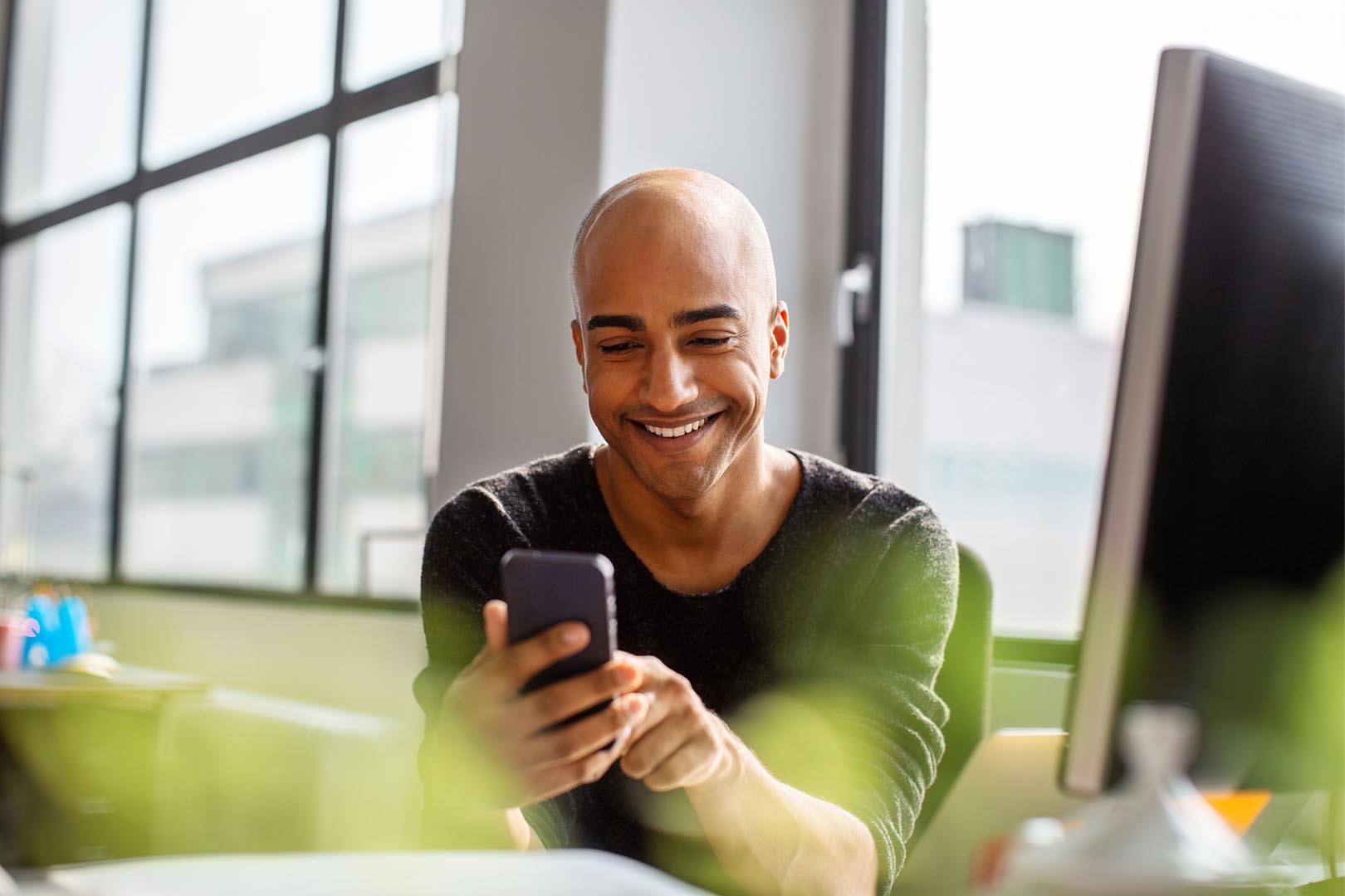 Man holding a phone, looking at it and smiling